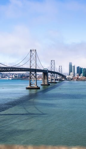 Bay Bridge spanning the water with the San Francisco skyline under a blue sky